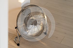 Silver metal ventilation fan on wooden floor at home