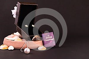 Silver necklace with pearl pendant and beautiful diamond earing set in brown gift box and seashells spreaded on black background.