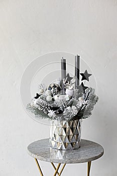 Silver New Year`s flower arrangement of Christmas tree branches and candles for a gift. New Year`s decor for the interior