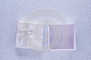 Silver open gift box on glitter silver background with copy space. Top view. Xmas, Valentines day or birthday party concept.