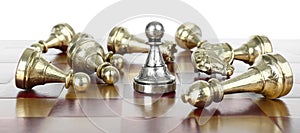 Silver pawn among fallen golden chess pieces on wooden board against white background