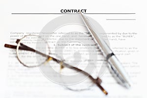 Silver pen and eyeglasses on sales agreement