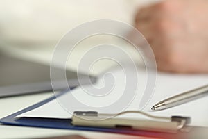 Silver pen lying on opened notebook sheet closeup