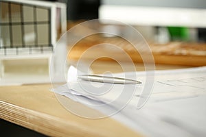 Silver pen lying at working table of architect with blueprints