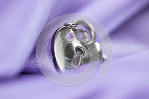 Silver pendent wrapped in violet satin fabric