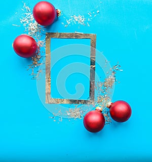 Silver photo frame and Christmas baubles on bright blue background.