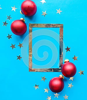 Silver photo frame and red Christmas baubles with stars on bright blue background.