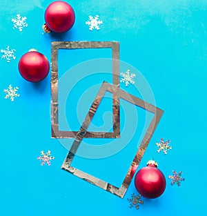 Silver photo frames and red Christmas baubles with stars on bright blue background.