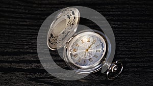 Silver pocket watch close up on a black wooden table