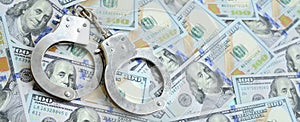 Silver police handcuffs lies on a many dollar bills