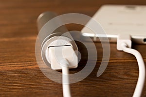 Silver power bank charging smartphone on wooden table