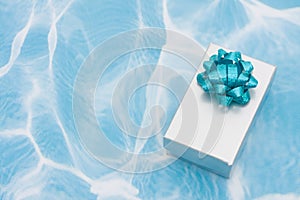 A silver present with bow on aqua background