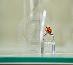 Silver ring with amber eye on a glass shelf