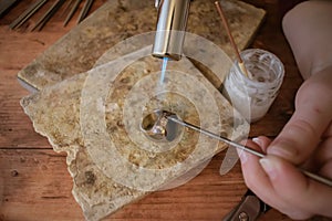 Silver ring being soldered on the work bench. Soldering using gas torch.