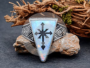 A silver ring with a cross design on a rock.