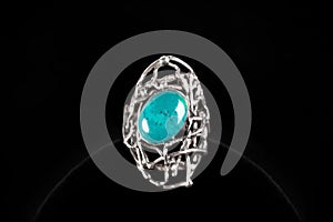 Silver ring with turquoise stone on black background.