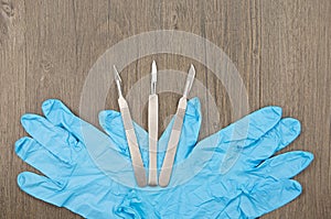 Silver scalpels and blue latex glove
