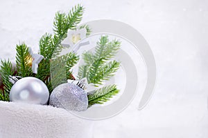 Silver shiny balls with fir branches and star lamps in fur bag on white background. Christmas, New Year