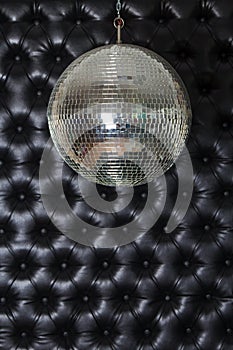 Silver shiny disco-ball on the black sofa background