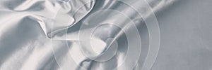 Silver silk background with a folds.  Abstract texture of rippled satin surface, long banner