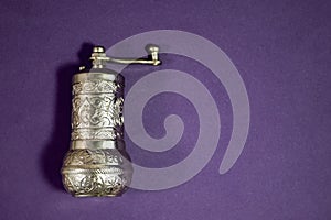 Silver Spice Mills on a Purple Background. East style. Retro Silver Pepper Mill, Corn and Crushed Colorful Pepper Isolated on