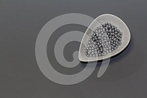 silver sprinkles on a white drop shaped plate on a gray background. Sprinklers for confectionery and pastry. Copy space photo