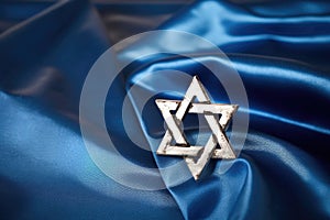 a silver star of david on a blue cloth background