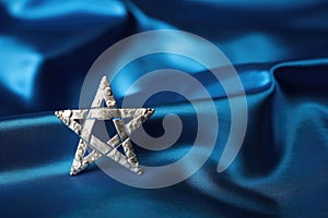 a silver star of david on a blue cloth background