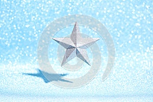 Silver star soars in space - Christmas tree decoration on a shiny blue background.