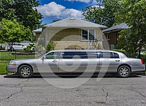 A silver stretch limo parked on the street of a residential area