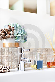 Silver tap with scent diffuser bottle in a modern bathroom