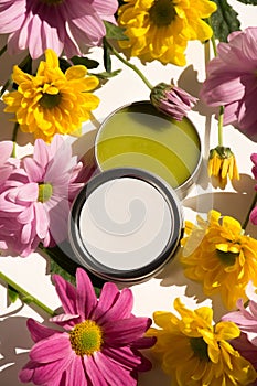 Silver tin filled with green balm on a table with clorful flowers