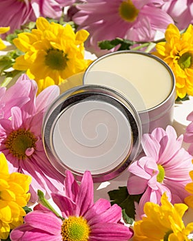 Silver tin filled with white balm on a table with clorful flowers