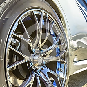 Silver tire rim with blue bolts of a white car