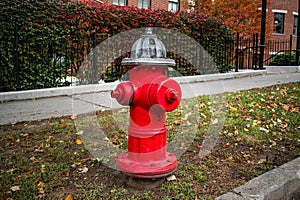 Silver-topped traditional red American style fire hydrant outside a modern housing block