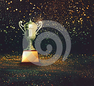 Silver trophy on abstract gold glitter background.