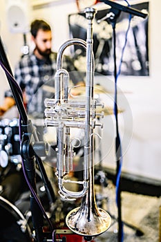 Silver trumpet in a recording studio, young man playing drums in an unfocused background