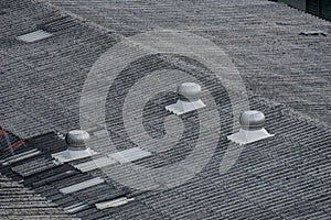 Silver turbo air ventilators on roof top of warehouse.