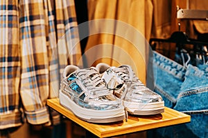 silver unisex sneakers shoes on shelf display in shop mall store. Store Of Shopping Center. retail sale