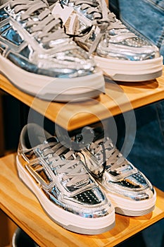 silver unisex sneakers shoes on shelf display in shop mall store. Store Of Shopping Center. retail sale