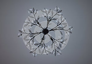A silver wall lamp imitating twigs with glass leaves. i