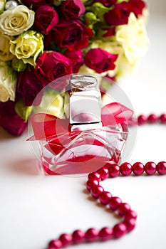 Silver wedding rings with perfume bottle and wedding bouquet of red and white roses