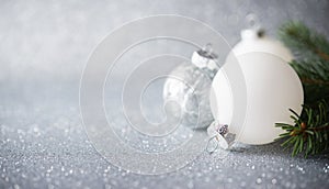 Silver and white xmas ornaments on glitter holiday background. Merry christmas card.