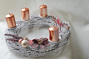 Silver wicker-work advent wreath with bronze coloured candles and christmass decoration