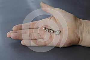 Silver word love with a padlock in an open male palm on a gray background