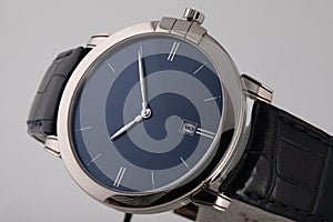Silver wristwatch with blue dial, silver clockwise, chronograph on black leather strap  on white background