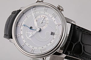 Silver wristwatch with white dial, silver clockwise, stopwatch and chronograph on black leather strap  on white background