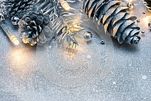 silvered pine cones and glowing lights garland on frosty background