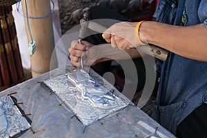 Silversmith craftsman carving elephant on a silver plate metal