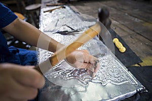 Silversmiths tools on the silver workplace. Silversmith using hammer and steel engraved pattern on silver plate for accessory